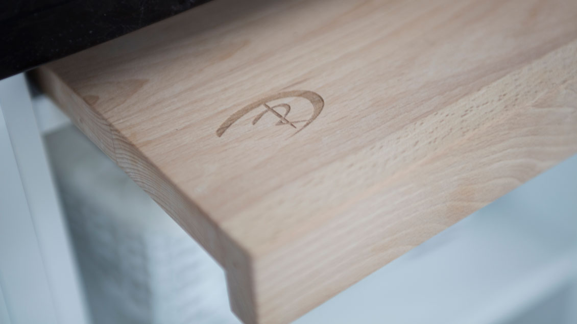 Logo naszej pracowni umieszczone w dyskretnym miejscu drewnianych mebli kuchennych na wymiar.