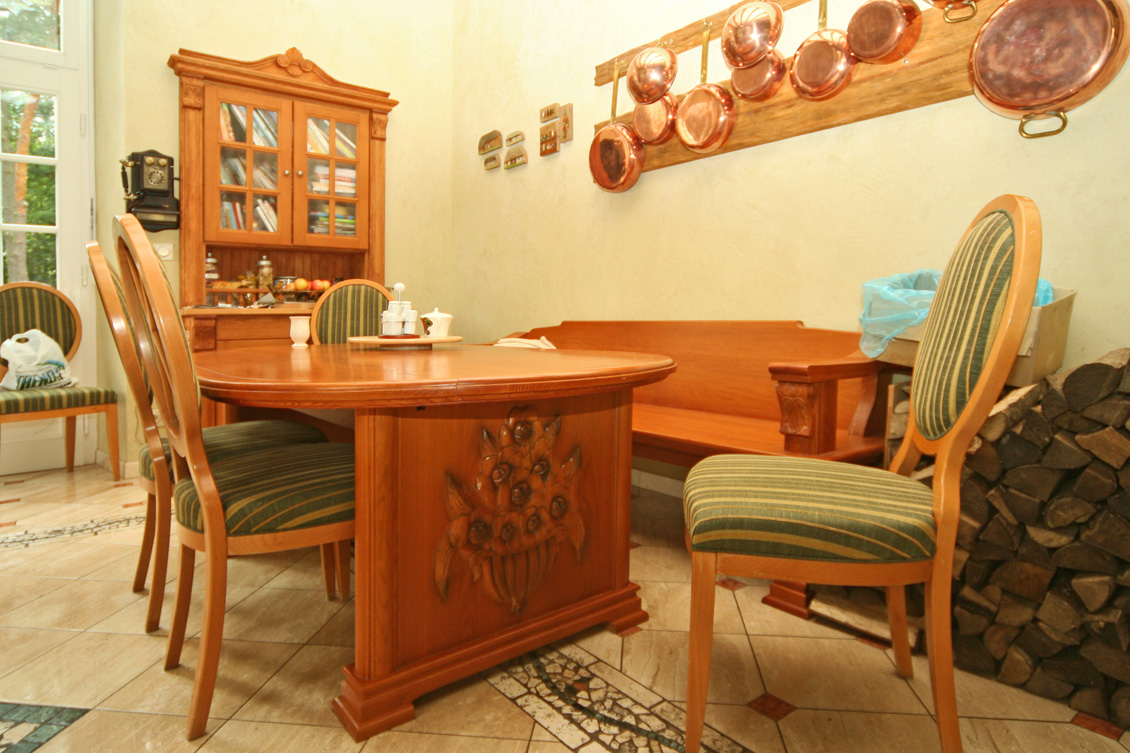 Kuchnia na wymiar połączona z jadalnią - wykonane z drewna meble w jadalnianej części pomieszczenia.