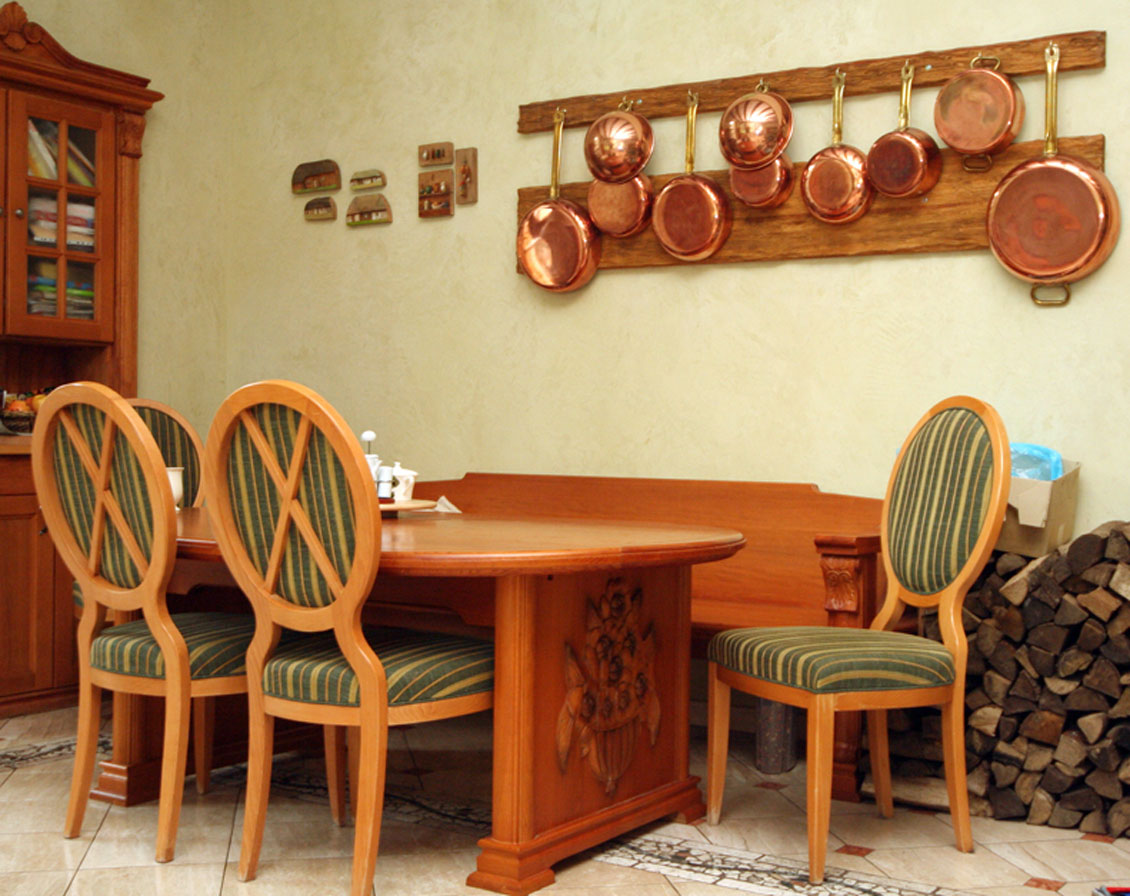 Kuchnia na wymiar połączona z jadalnią - meble drewniane w jadalnianej części pomieszczenia. Stół zdobi piękna płaskorzeźba z kwiecistym ornamentem.
