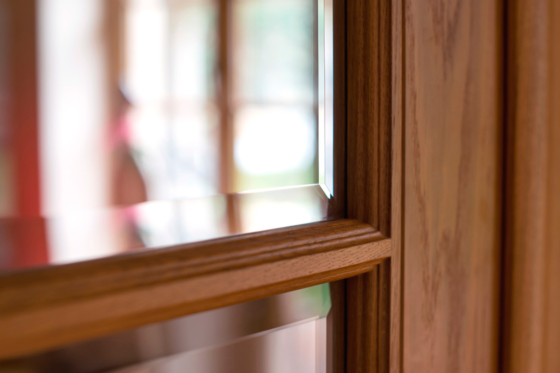 Fragment brązowego, drewnianego okna na wymiar - zbliżenie na stolarkę okienną.