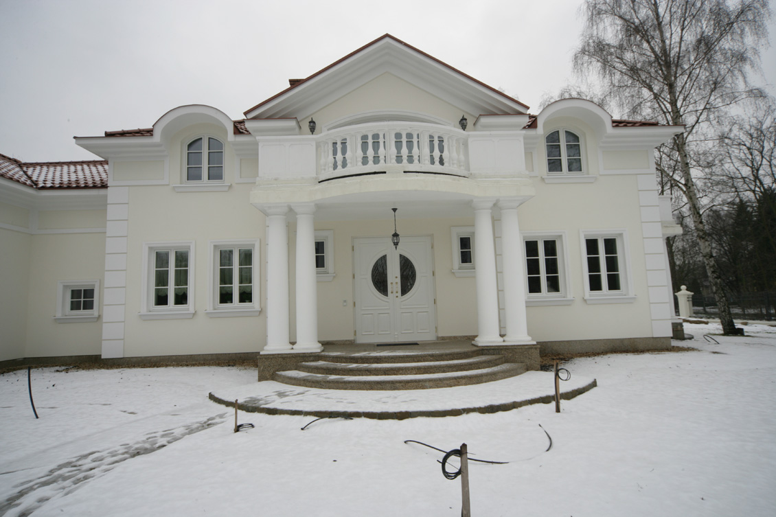 Front okazałego domu jednorodzinnego, białe drewniane okna i białe drzwi zewnętrzne i biała elewacja - luksusowy wygląd.