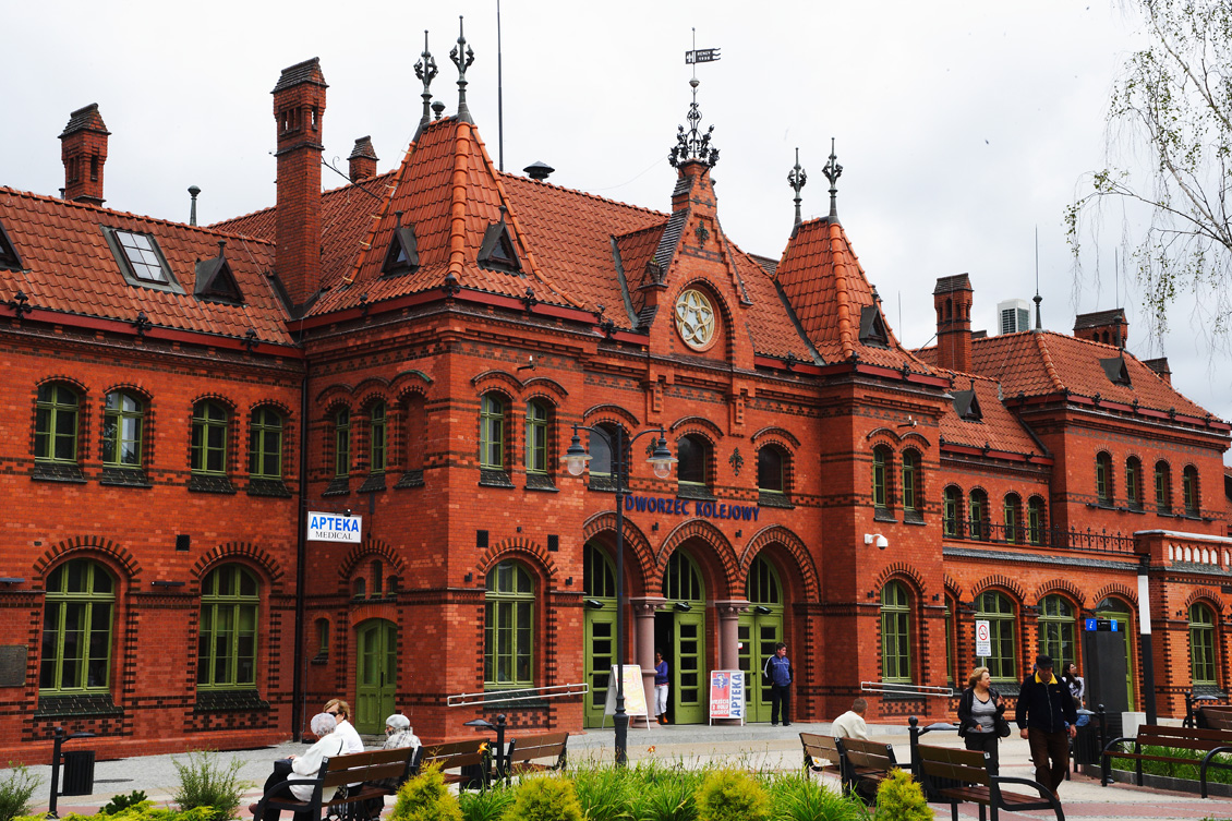 Piękne drewniane okna skrzynkowe na wymiar, ceglany, zabytkowy budynek dworca kolejowego w Malborku, drewniane okna i drzwi zewnętrzne w kolorze jasnozielonym, drewno po renowacji, rewitalizacja okien i drzwi zabytkowych.