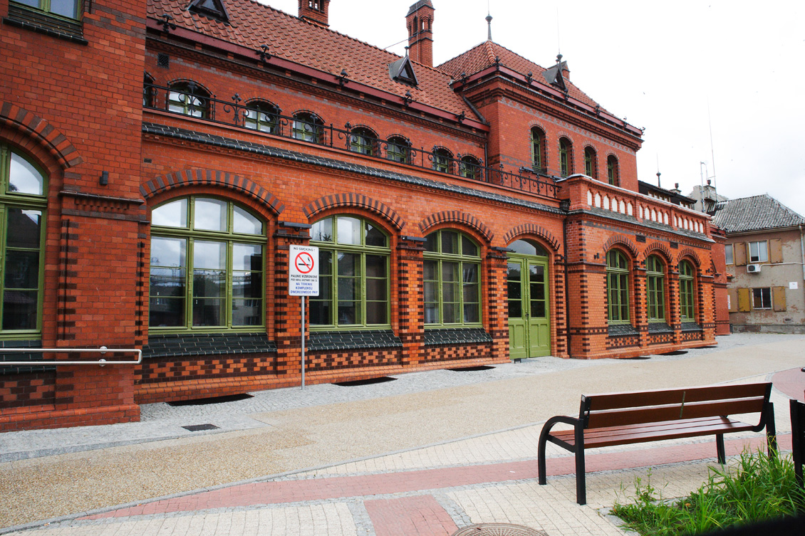 Drewniane okna skrzynkowe na wymiar, widok prawej części zabytkowego budynku dworca kolejowego w Malborku, drewniane okna i drzwi zewnętrzne w kolorze jasnozielonym, rewitalizacja okien i drzwi zabytkowych, drewno po renowacji.